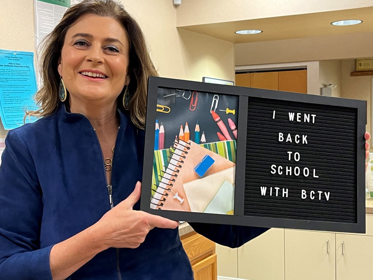 A woman holding up a sign that reads "I went back to school with BCTV". 