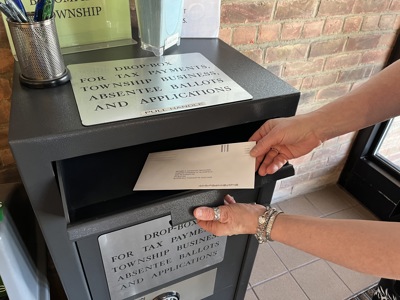 a Drop Box for Tax Payments and Township Business with a person inserting an envelope addressed to the Township Treasurer