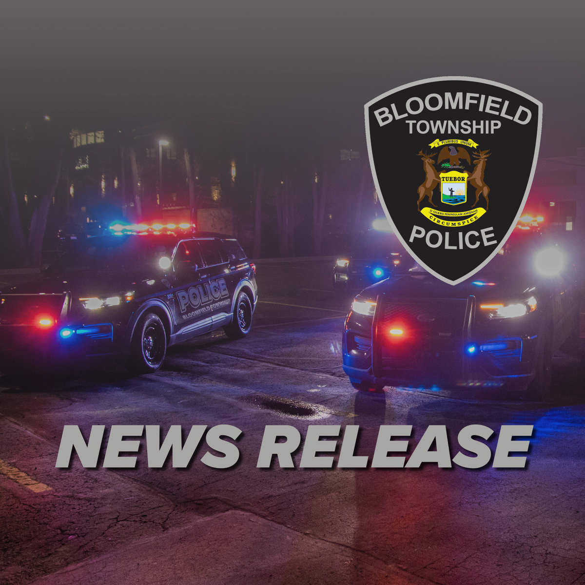 Two lit up Bloomfield Township police cars in the night with the Bloomfield Township Police Department logo in front of them. 