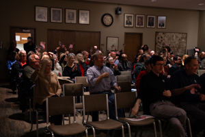 Audience at Township hall smiling and waving American flags