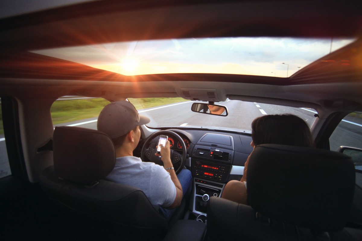 A man driving while looking at his phone with a woman passenger for Bloomfield Township Distracted Driving