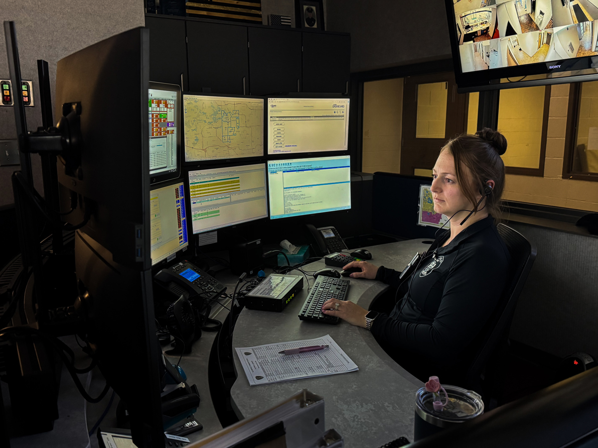 A dispatcher sitting at her work desk looking at computers. 