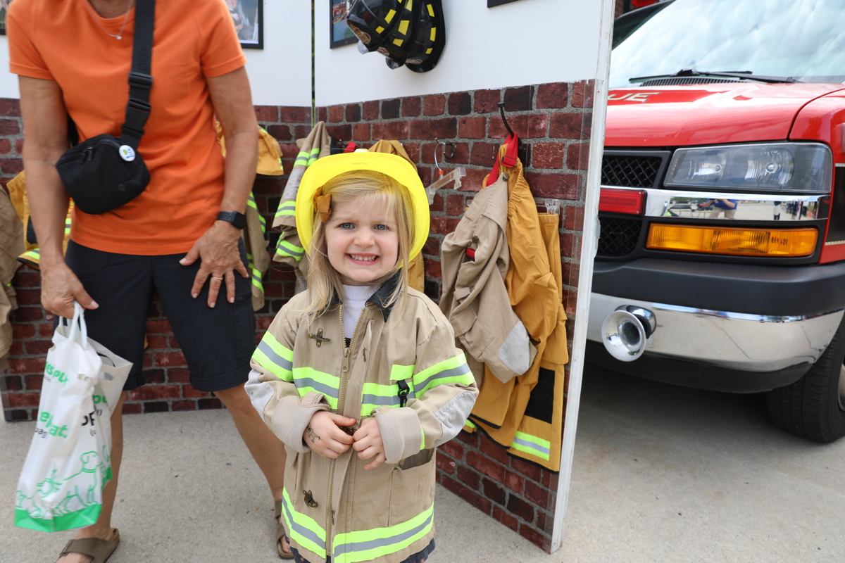 Little girl dressed up in a firefighting uniform and hat. 