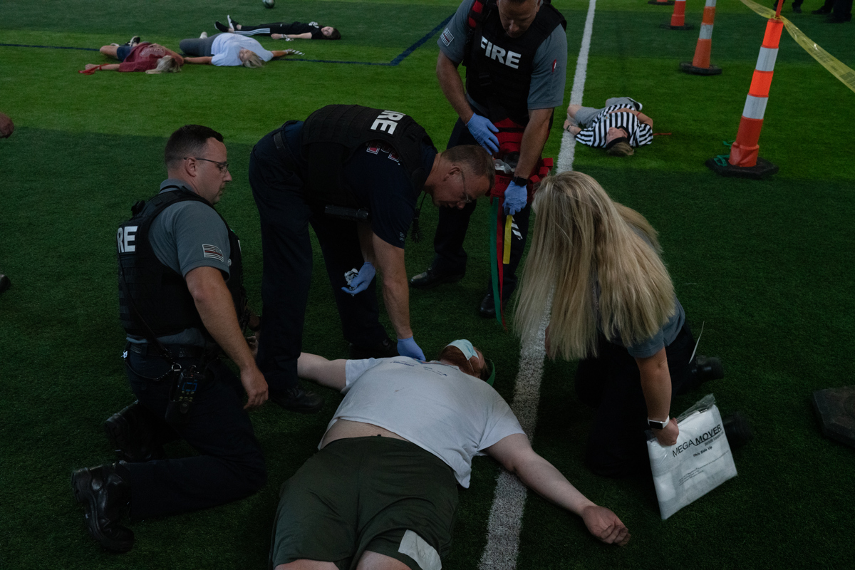 A group of first responders aiding to a fake injured person on the ground for a scenario. 