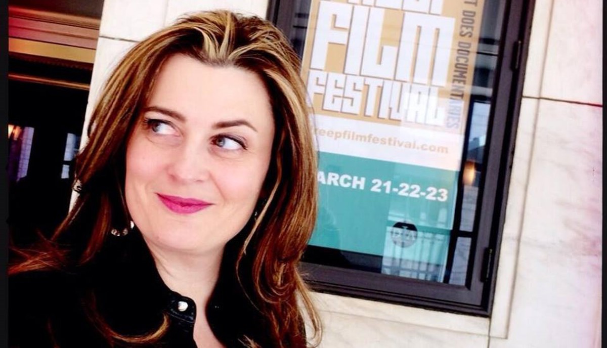 A woman standing outside of a film festival sign. 