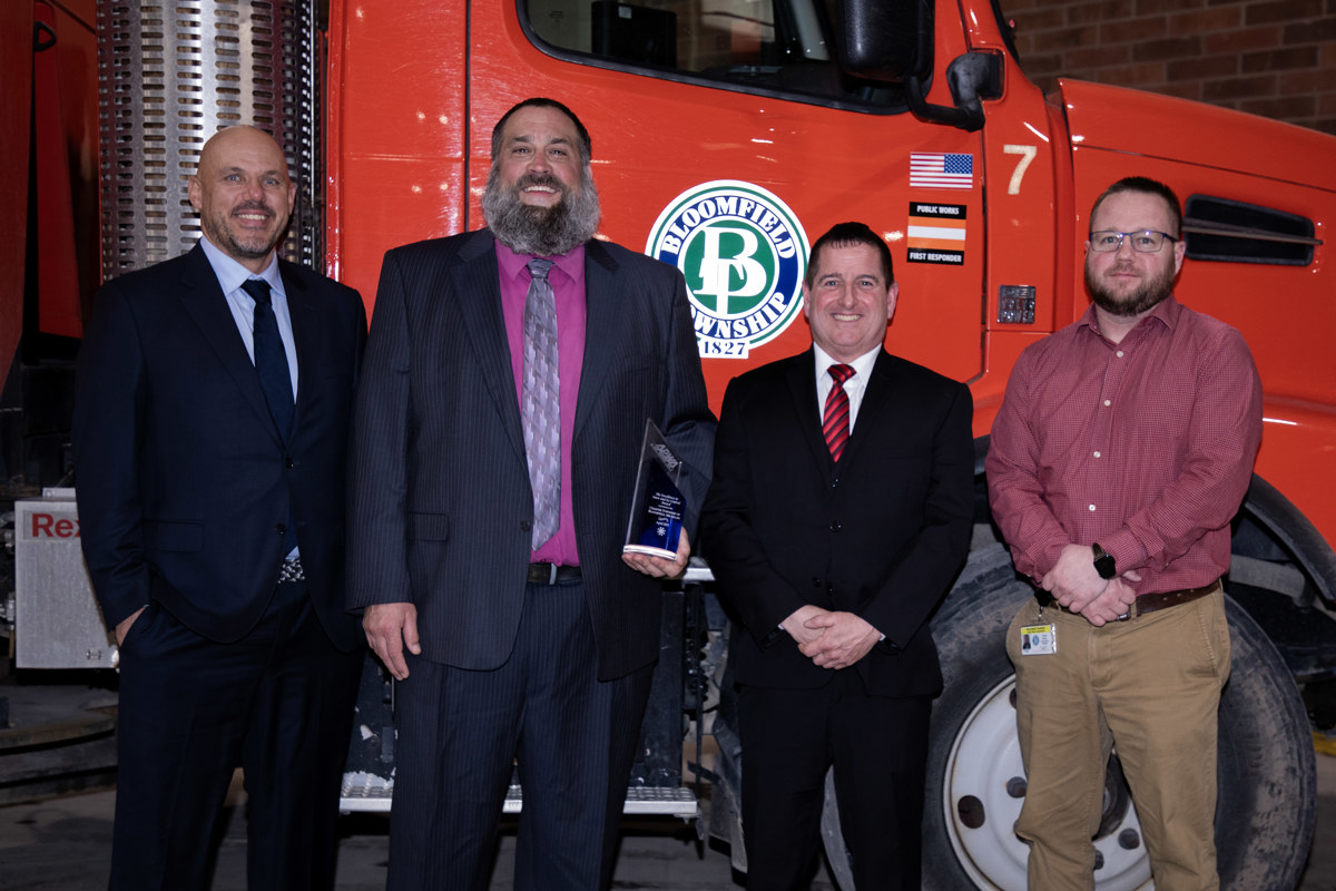 Four men holding an award and standing in front of a DPW truck. 