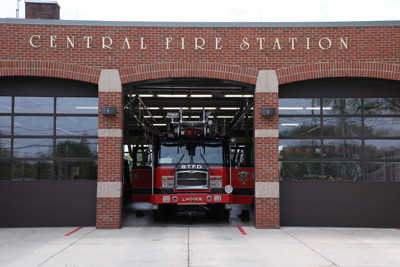 straight on view of Central Fire Station with Fire Dept ladder truck inside middle bay with door open. Doors on either side are closed.