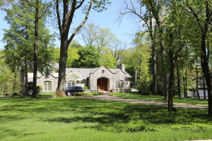 The outside of a house with a long driveway surrounded by trees.