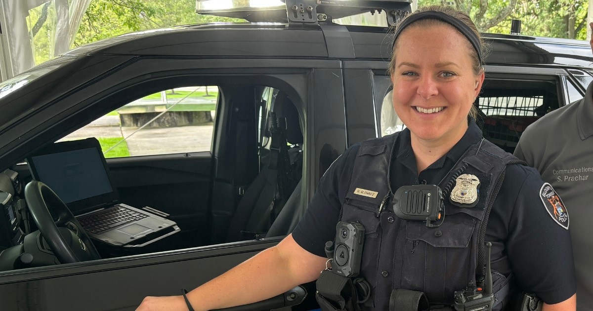 A police officer in uniform next to her police car. 